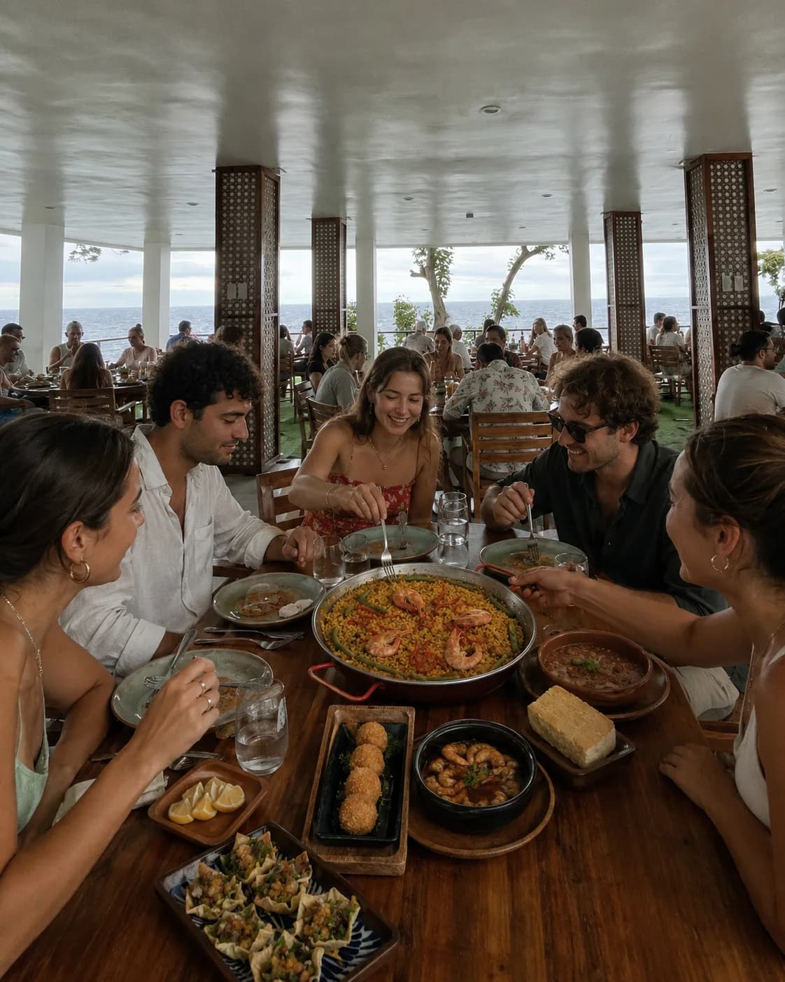 A paella pan with prawns and green beans on a clifftop table above the Bohol Sea in Camiguin, with croquetas and gambas al ajillo alongside