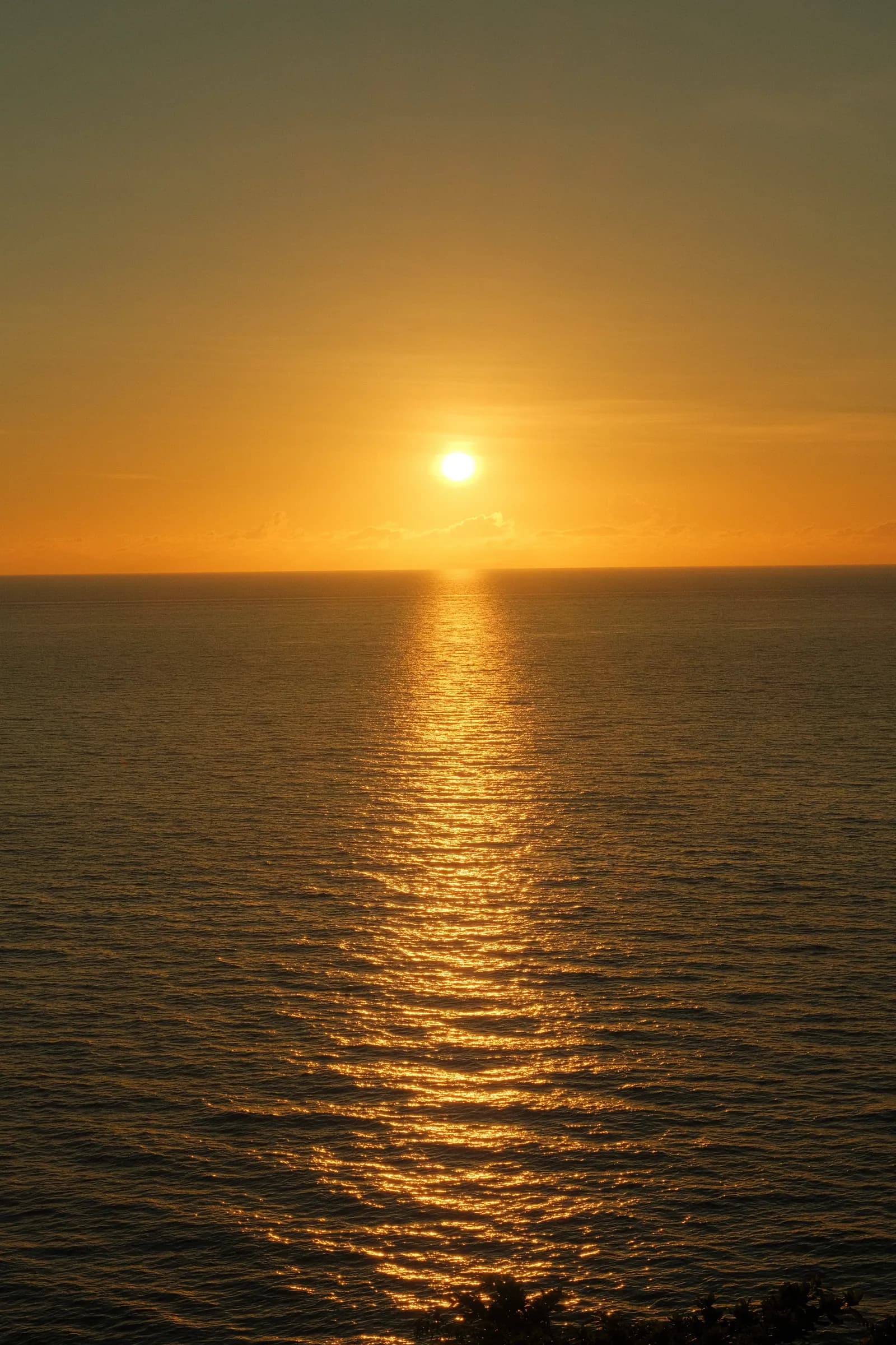 The sun going down over the Bohol Sea from a Camiguin clifftop, the water turning copper