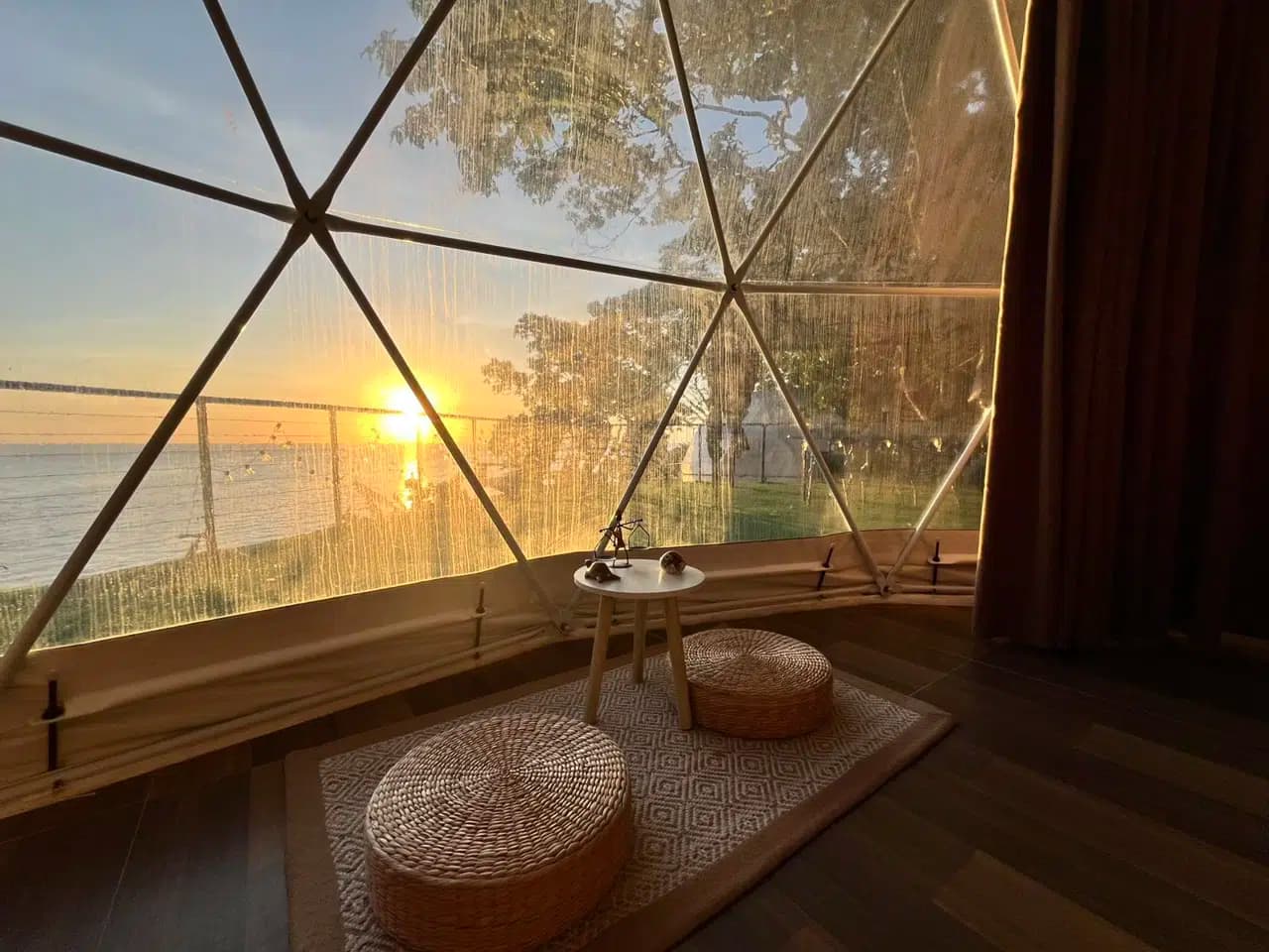 Cliff-edge glamping above the Bohol Sea at sunset in Camiguin — a canvas room with a private deck over the water